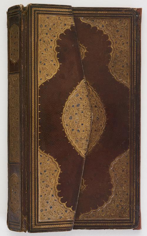 Brown leather book binding closed, flap covers half of the front panel. Decorated with central medallions and cornerpieces of gold-stamped floral motifs and cloudbands, the flower heads picked out in blue, spine with calligraphic panel.