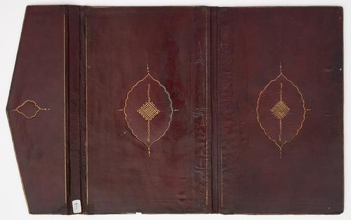 Inner cover of dark red leather bookbinding, laid flat with spine in the middle and envelope flap on the left. Both covers feature identical thin golden oval medallion motifs. Envelope flap has similar smaller motif. Thin golden border lining the perimeter of each cover and envelope flap is mostly faded.