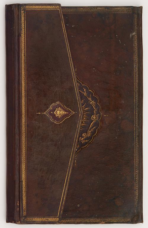 Front of closed dark brown leather bookbinding, with envelope flap on the left partially covering embossed golden oval medallion with rope-like motifs in the centre of the cover. Envelope flap has smaller embossed golden motif in the middle. Faded golden coiled border lines perimeter of the cover and envelope flap.