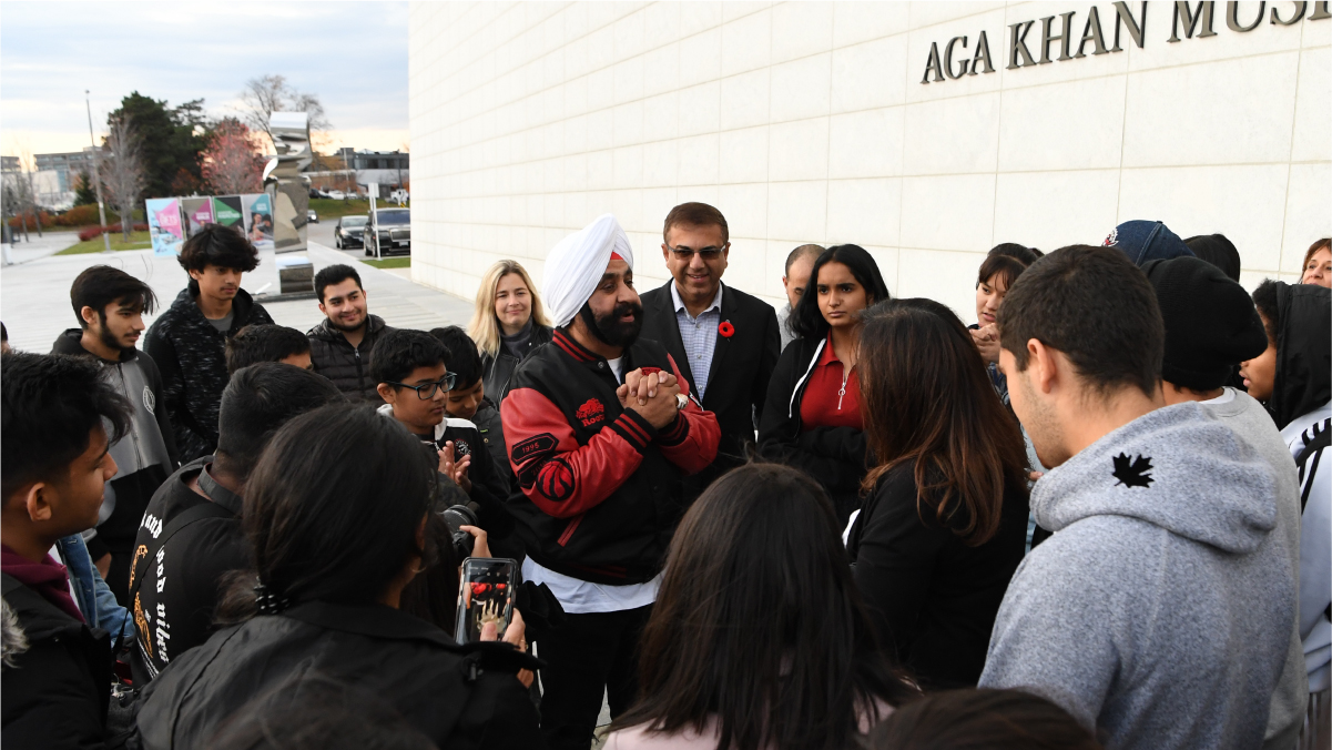 Outside the Museum, Nav Bhattia addresses a crowd of kids and Museum staff with his hands clasped.