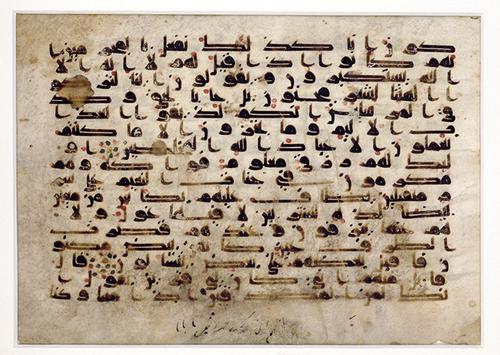 Beige rectangular page with 16 lines of bold, black calligraphic text, accented with red dots. The page is weathered and some parts of the text is faded, with stains on the page.