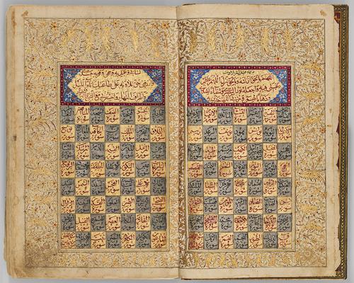 Book opened to a highly illuminated double page spread. Text boxes feature an illuminated heading, burgundy boarder surrounding red text on gold and a blue floral background. The lower section of the text boxes features gold and blue checkered boxes with text inside each.