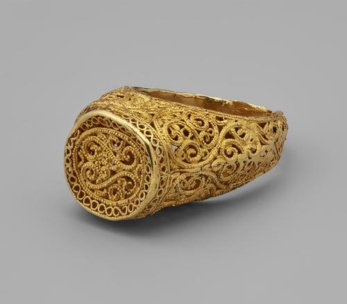 Front view of a stirrup-shaped ring gold ring with delicate filigree