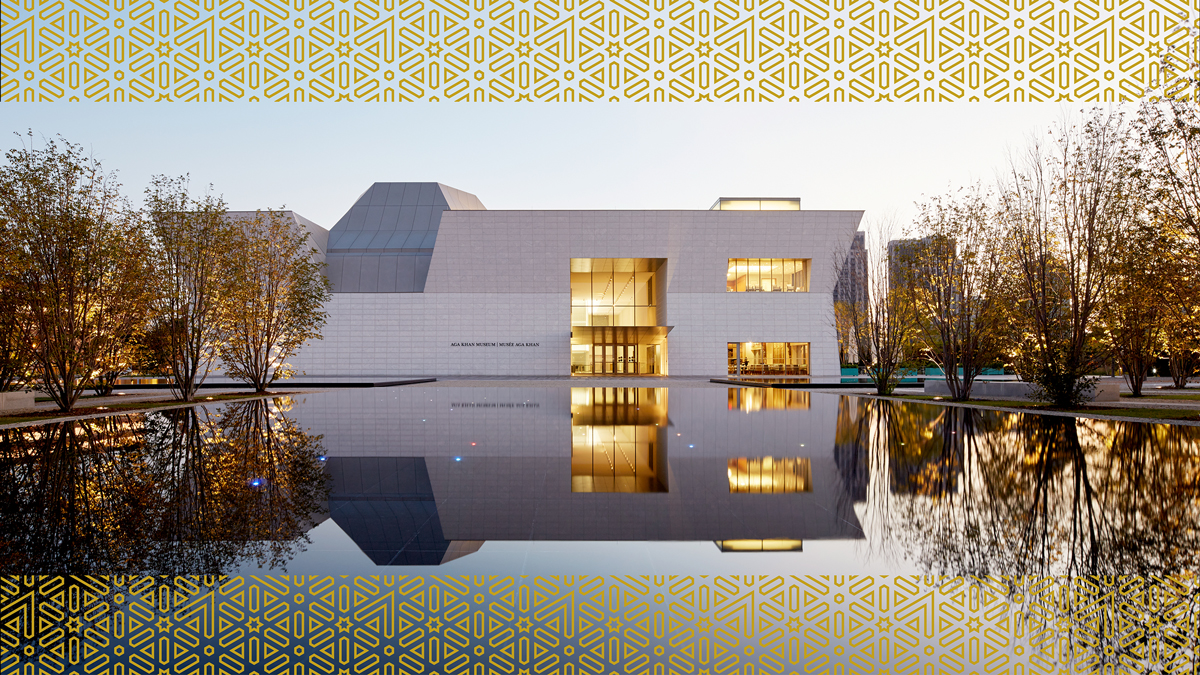 The Aga Khan Museum at dusk, seen from a distance, so that the building’s upside-down reflection is also visible in the Museum’s central Reflecting Pool.