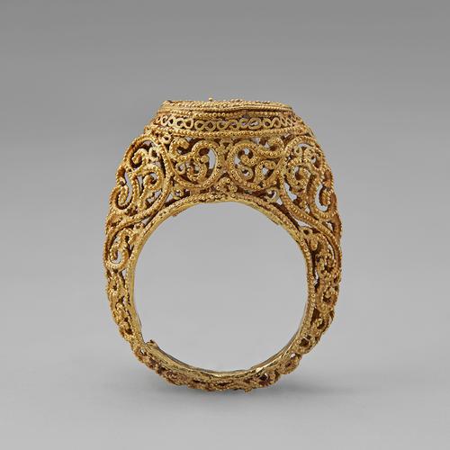 Side view of the golden ring standing straight up on its band. Side view of the filigree and granulation that create this ring.