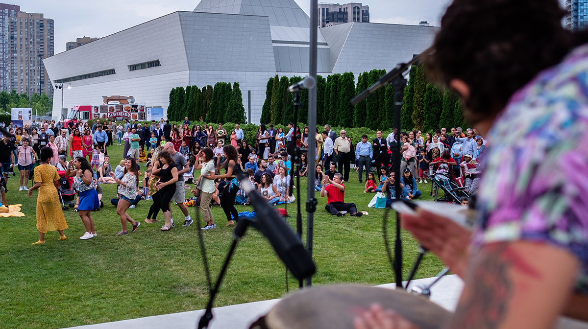 A crowd of people take in a drumming performance outside the Aga Khan Museum.