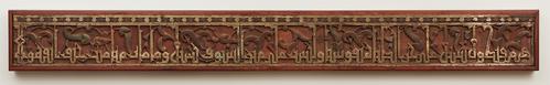 Pine beam of rectangular form, the face carved with a single line of strong kufic interlaced with tendrils terminating in split palmettes and single leaves, plain white stripe below.