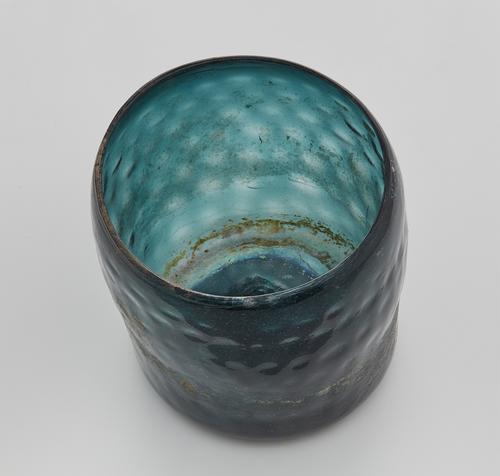 Interior of a Blue/Green glass beaker of cylindrical form with a rounded honeycomb design.