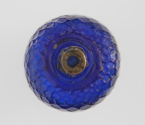 View down the neck of a Blue glass bottle with globular body and tapering narrow neck with a trailed collar at the base, the body impressed with a honeycomb design.