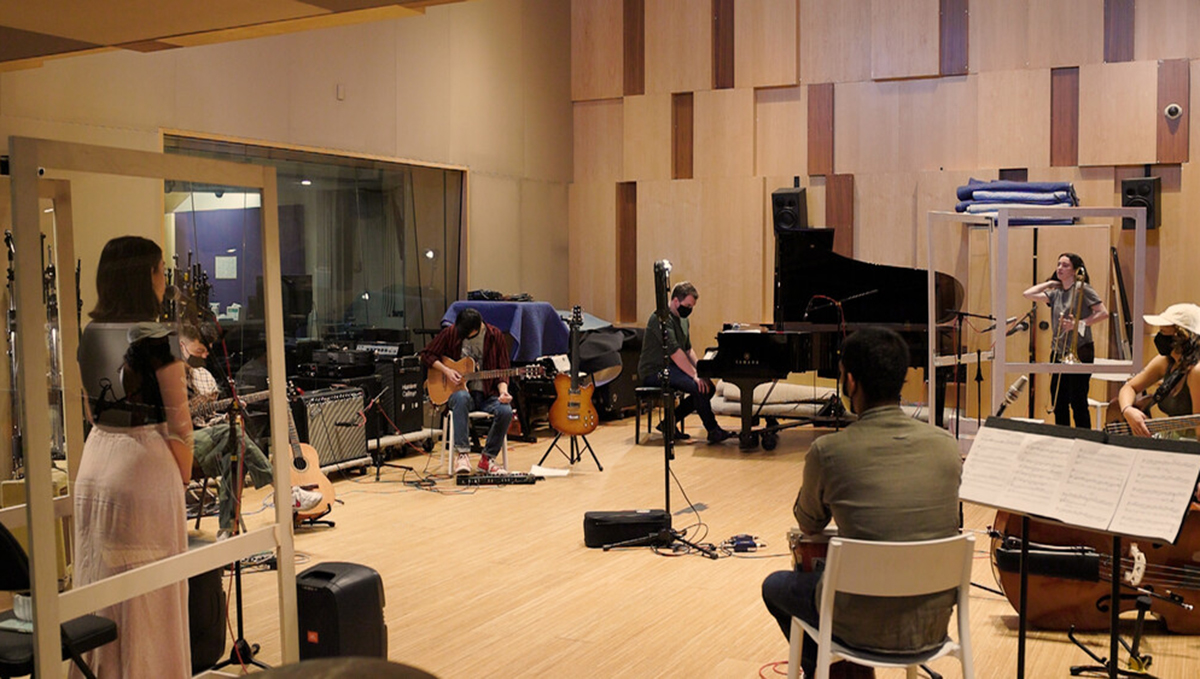 Music students rehearsing in a high-walled music studio or practice space.