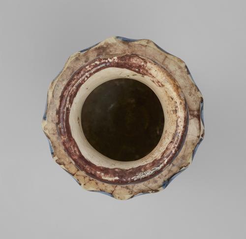 View looking into the interior of a brown and blue lustre on a cream coloured ceramic vase. Dark brown lip of the neck and beige shoulder of the sides can be seen.