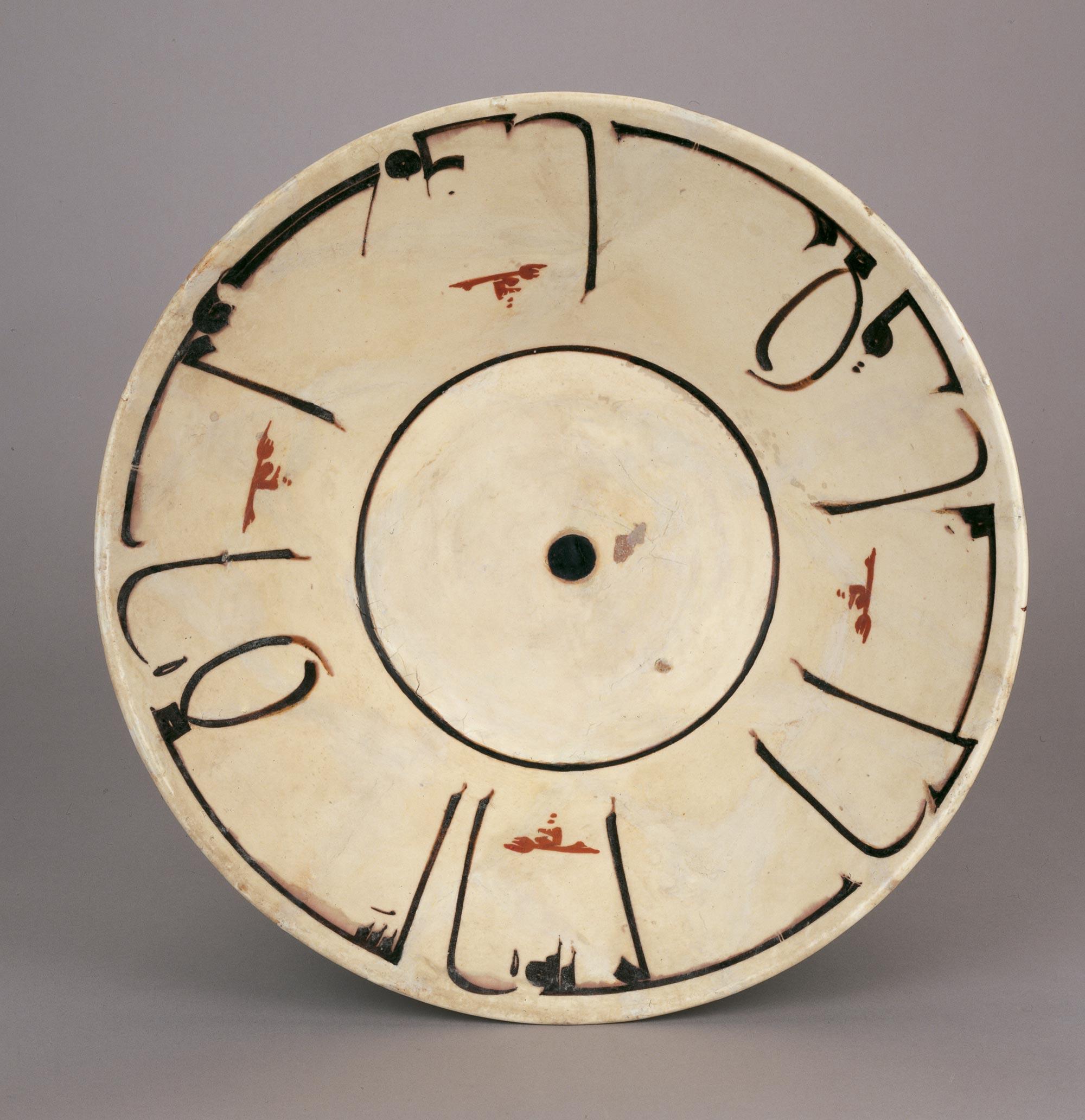 An off-white bowl from 10th-century Iran with black Arabic calligraphy around the perimeter.