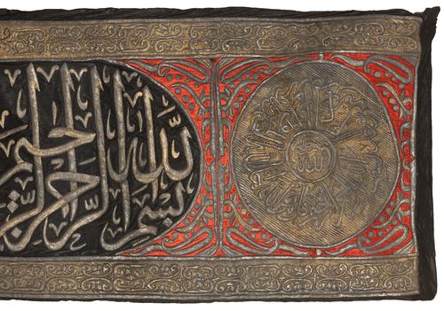 Black textile fragment, embroidered with  gold Qur’anic verses, red decoration separates the main verses with a roundels contain further Qur’anic references at the beginning edge.