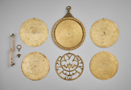 Astrolabe disassembled to see the front of all plates, laid out in a grid.
