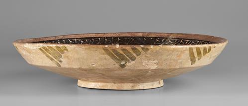 Side of shallow bowl, beige colour, outside walls decorated with repetative diagonal green lines creating a trianular shape