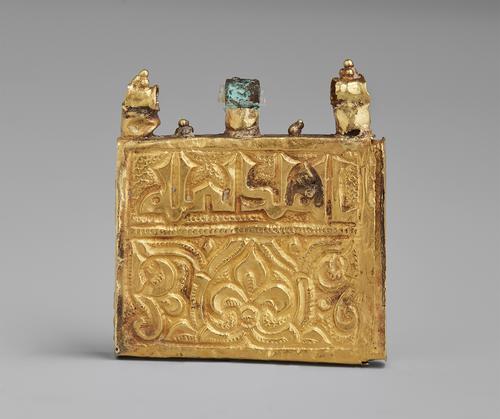 Opposite side of the gold amulet qur’an case. Square gold thin box with three loops on the top where it would be hung as a pendant. Inscription and engraving on the front panel.