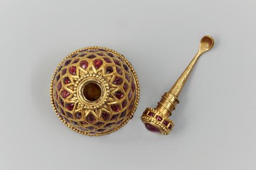 Top view of the small jewelled container encrusted with red gemstones. View of the top twisted off and the miniature spoon attached to the inside of the lid sitting separately.