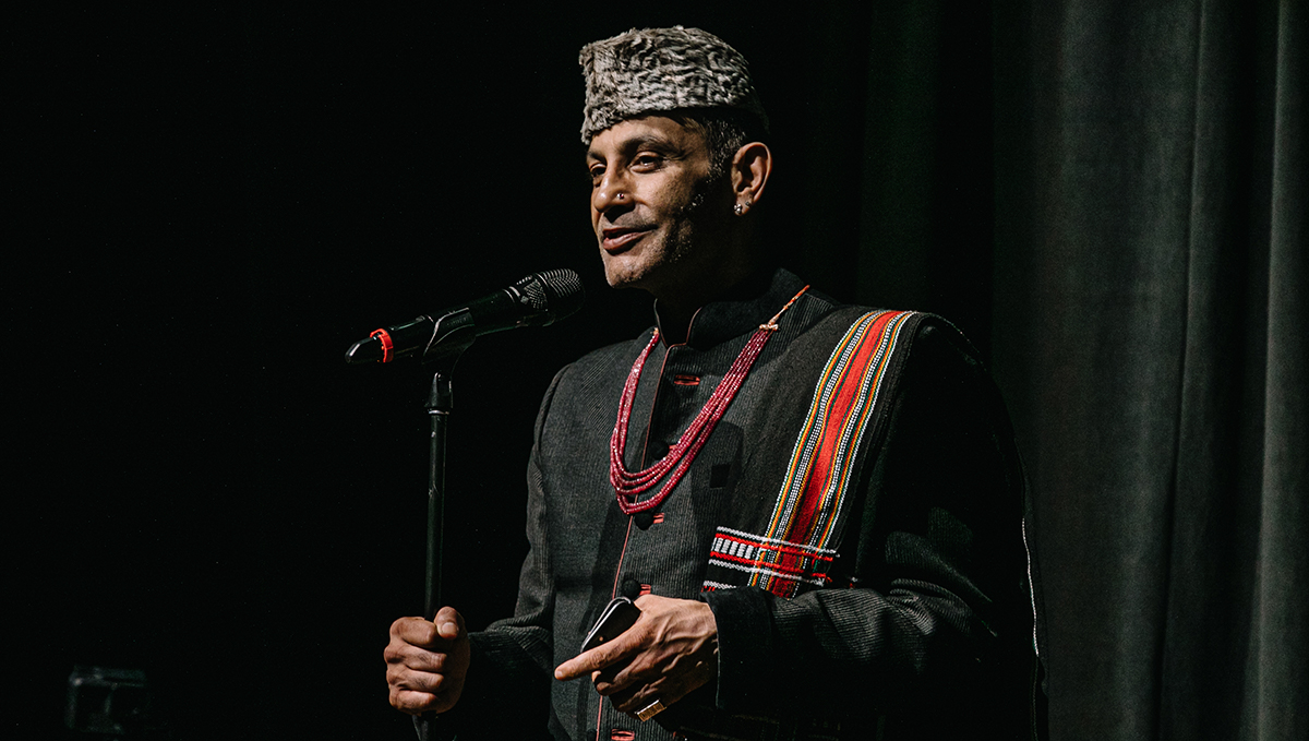 Amirali Alibhai, the Aga Khan Museum's Head of Performing Arts, speaks into the microphone while standing on the stage of the Museum's Auditorium. 