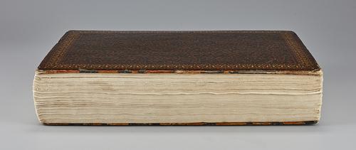 Side of closed manuscript showing cream-coloured pages and lacquered cover.