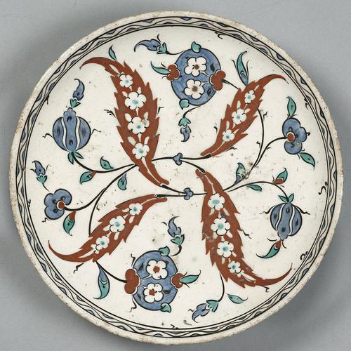  Ceramic dish decorated with four entwined "saz" leaves and peonies, each leaf is filled with small rosettes. Painted in red, lavender and turquoise-blue against an opaque-white ground.   