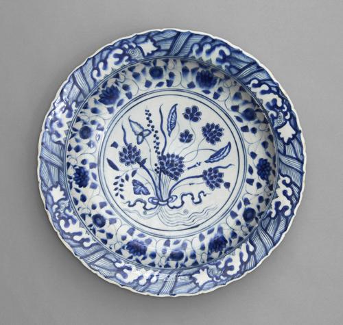 Dish follows a Chinese model so closely that it might have passed for a Chinese original if the body had been translucent like porcelain. Blue and white designs cover the white plate with a foliage design in the centre.