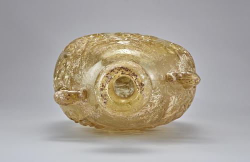 Flat-sided elongated oval form Bottle laying on its side, view into the constricted neck with spherical mouth, view of the two small applied loop handles on the shoulder, yellow, brown with slight iridescence.