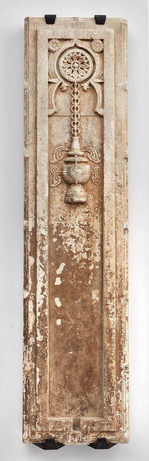 Tall rectangular form carved in deep relief with a design of an incense burner issuing smoke and suspended from a broad linked chain from a floral form medallion, set within a broad plain raised border indented at the base. 