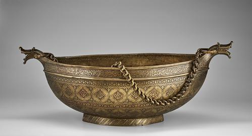 Narrow brass bowl with small dragon heads on each pointed end. A chain is attached to each dragon head. The bowl is heavily engraved, with bands of floral motifs on the outside and geometric designs on the interior. A Persian poem is inscribed around the exterior rim.